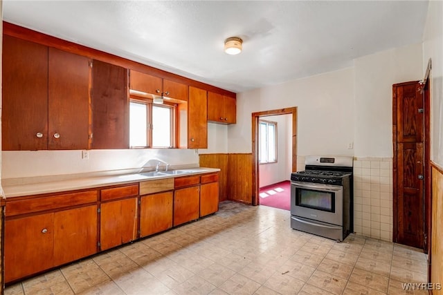 75 Schutrum St, Buffalo, NY 14212 - kitchen with stainless steel range with gas cooktop, a wainscoted wall, plenty of natural light, and brown cabinetry