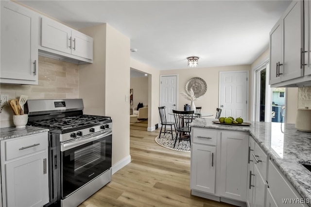 101 Kurtz Ave, Lancaster, NY 14086 - kitchen with stainless steel gas stove, backsplash, light wood finished floors, a peninsula, and light stone counters