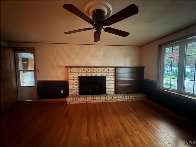 124 N Way, Camillus, NY 13031 - unfurnished living room with wood finished floors, a ceiling fan, wainscoting, and a fireplace