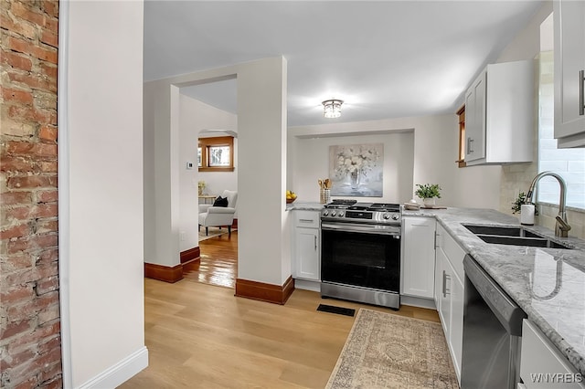 111 Montrose Ave, Buffalo, NY 14214 - kitchen featuring stainless steel appliances, light wood-style floors, arched walkways, light stone counters, and white cabinetry