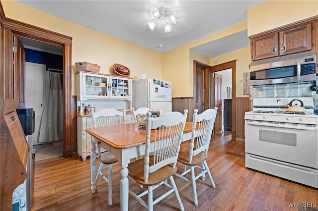 2469 Seneca St, West Seneca, NY 14210 - dining room with a wainscoted wall, ceiling fan, and light wood-style floors
