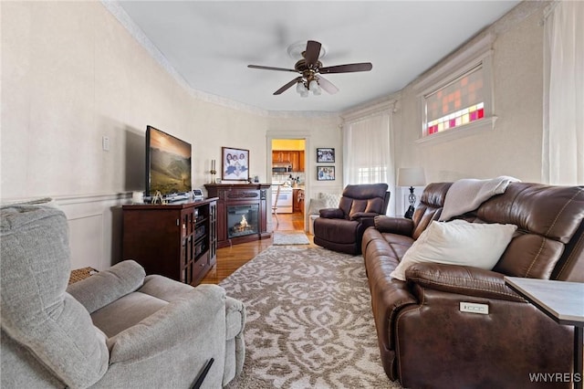 2469 Seneca St, West Seneca, NY 14210 - living room featuring a ceiling fan, wood finished floors, ornamental molding, and a glass covered fireplace