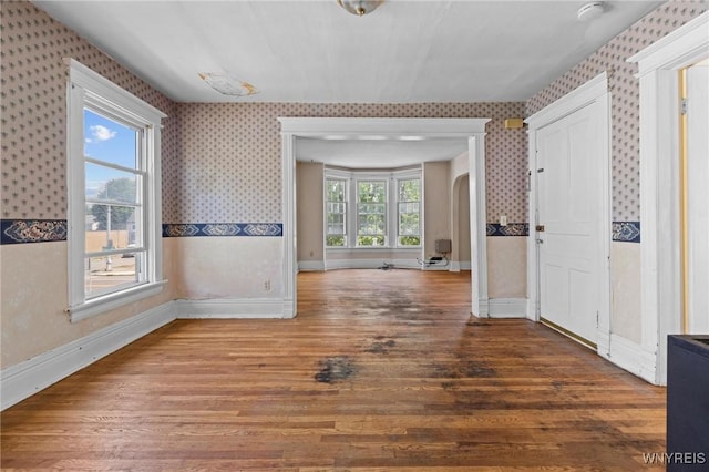 2469 Seneca St, West Seneca, NY 14210 - empty room with wallpapered walls, wood finished floors, a smoke detector, and arched walkways