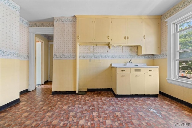 2469 Seneca St, West Seneca, NY 14210 - kitchen featuring wallpapered walls, wainscoting, cream cabinetry, and light countertops