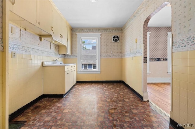 2469 Seneca St, West Seneca, NY 14210 - kitchen with brick patterned floors, light countertops, wallpapered walls, arched walkways, and a wainscoted wall