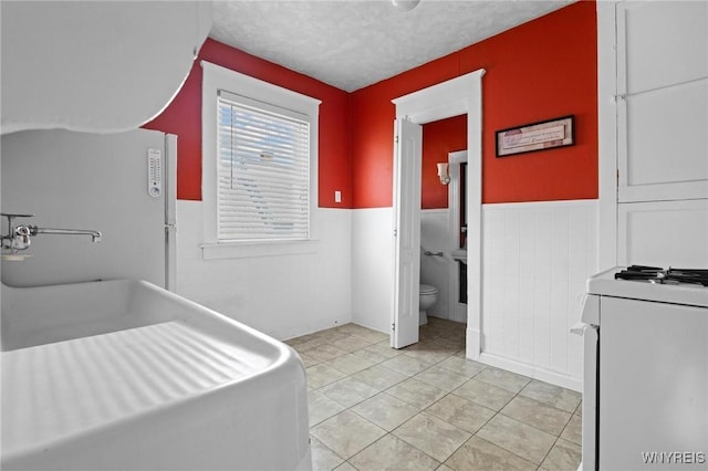 2469 Seneca St, West Seneca, NY 14210 - laundry room featuring wainscoting, light tile patterned flooring, and a textured ceiling
