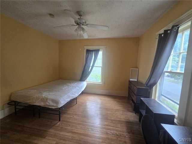 826 Lancaster Ave, Syracuse, NY 13210 - bedroom featuring multiple windows, hardwood / wood-style floors, a textured ceiling, and ceiling fan