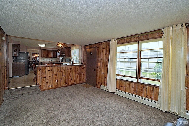4 Windtree Ln, West Seneca, NY 14224 - kitchen with dark countertops, freestanding refrigerator, wooden walls, a peninsula, and carpet flooring