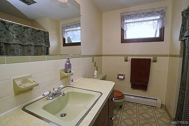 4 Windtree Ln, West Seneca, NY 14224 - full bathroom featuring baseboard heating, tile walls, a textured ceiling, vanity, and wainscoting