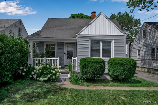 1871 Eggert Rd, Amherst, NY 14226 - bungalow featuring covered porch, a chimney, a front yard, and roof with shingles