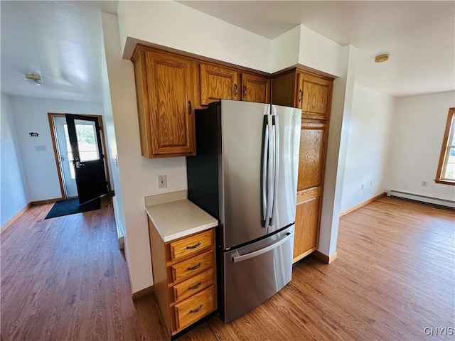3370 Hicks Rd, Scipio, NY 13118 - kitchen featuring freestanding refrigerator, a baseboard heating unit, wood finished floors, brown cabinets, and light countertops