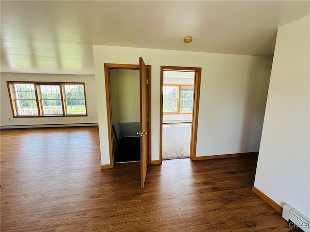 3370 Hicks Rd, Scipio, NY 13118 - empty room with baseboard heating, dark wood-style floors, a baseboard heating unit, and plenty of natural light