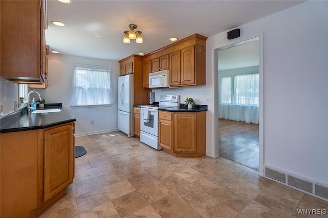 165 Kelvin Dr, Tonawanda, NY 14223 - kitchen featuring white appliances, dark countertops, healthy amount of natural light, brown cabinetry, and recessed lighting