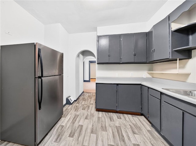 896-898 S Plymouth Ave, Rochester, NY 14608 - kitchen featuring freestanding refrigerator, light wood-type flooring, open shelves, arched walkways, and light countertops