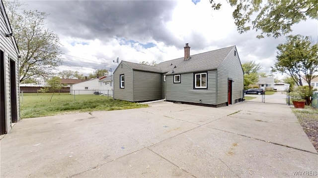 370 W W Girard Blvd, Tonawanda, NY 14217 - back of property featuring concrete driveway, a gate, a chimney, and roof with shingles