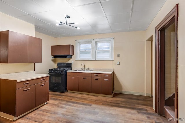 146 Longnecker St, Buffalo, NY 14206 - kitchen featuring black gas range oven, light countertops, light wood-type flooring, under cabinet range hood, and a drop ceiling