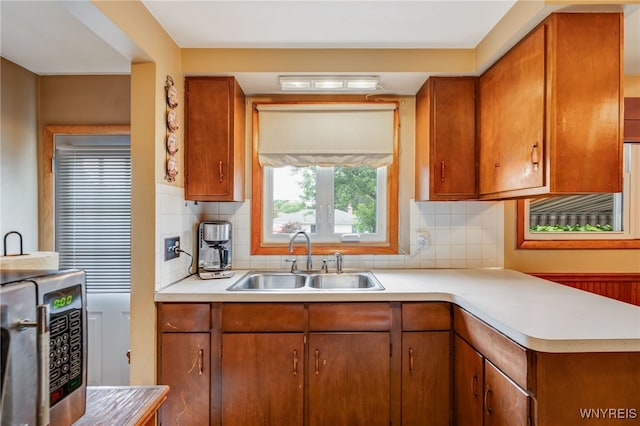 7 Cannas Ct, Cheektowaga, NY 14227 - kitchen featuring stainless steel microwave, light countertops, brown cabinets, and tasteful backsplash