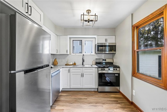 374 Dewey Ave, Buffalo, NY 14214 - kitchen with appliances with stainless steel finishes, a chandelier, decorative backsplash, and white cabinets
