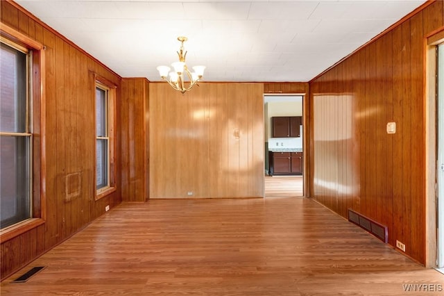 1329 Clinton St, Buffalo, NY 14206 - unfurnished dining area with a chandelier, wood finished floors, wooden walls, and plenty of natural light