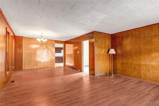 1329 Clinton St, Buffalo, NY 14206 - spare room with a chandelier, wooden walls, and wood finished floors
