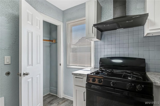 40 Decker St, Buffalo, NY 14215 - kitchen featuring gas stove, wall chimney exhaust hood, decorative backsplash, light wood finished floors, and white cabinets