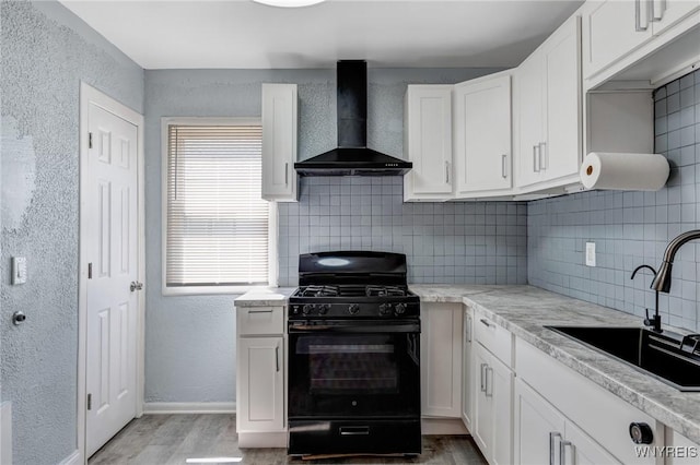 40 Decker St, Buffalo, NY 14215 - kitchen with black gas stove, wall chimney range hood, tasteful backsplash, light wood-style floors, and a textured wall