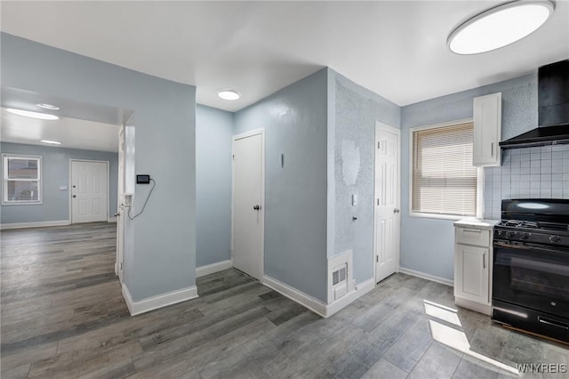 40 Decker St, Buffalo, NY 14215 - kitchen featuring black range with gas cooktop, wall chimney exhaust hood, white cabinets, wood finished floors, and light countertops