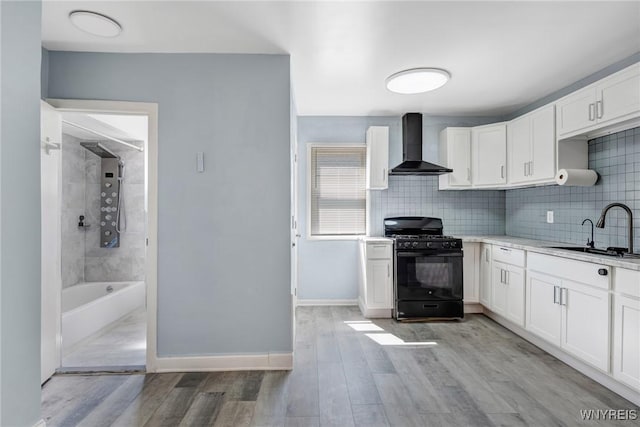 40 Decker St, Buffalo, NY 14215 - kitchen with wall chimney exhaust hood, gas stove, white cabinetry, and decorative backsplash