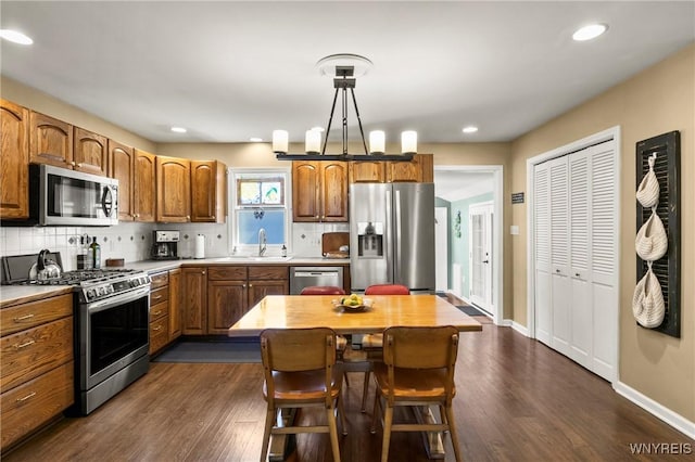 715 Brighton Rd, Tonawanda, NY 14150 - kitchen with stainless steel appliances, decorative backsplash, brown cabinetry, dark wood-type flooring, and recessed lighting
