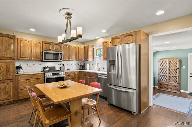 715 Brighton Rd, Tonawanda, NY 14150 - kitchen featuring appliances with stainless steel finishes, brown cabinetry, tasteful backsplash, hanging light fixtures, and dark wood finished floors
