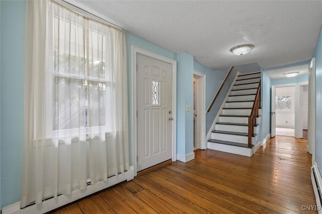 16 Onondaga St, Skaneateles, NY 13152 - foyer entrance featuring a baseboard heating unit, a textured ceiling, stairs, hardwood / wood-style floors, and baseboard heating