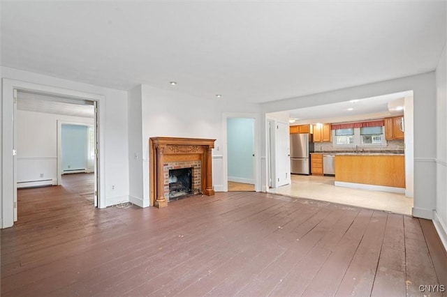 16 Onondaga St, Skaneateles, NY 13152 - unfurnished living room featuring light wood-style flooring, a brick fireplace, and baseboard heating