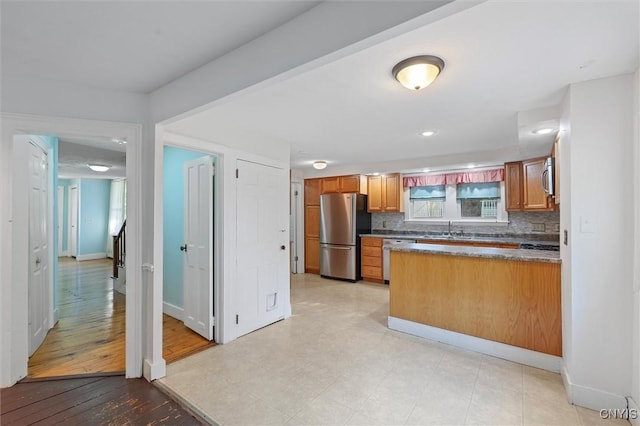 16 Onondaga St, Skaneateles, NY 13152 - kitchen with appliances with stainless steel finishes, a peninsula, brown cabinets, and decorative backsplash
