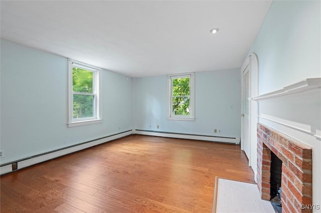 16 Onondaga St, Skaneateles, NY 13152 - unfurnished living room with a baseboard heating unit, wood finished floors, and a brick fireplace