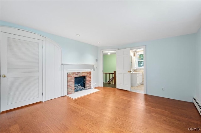 16 Onondaga St, Skaneateles, NY 13152 - unfurnished living room featuring wood finished floors, baseboard heating, and a brick fireplace