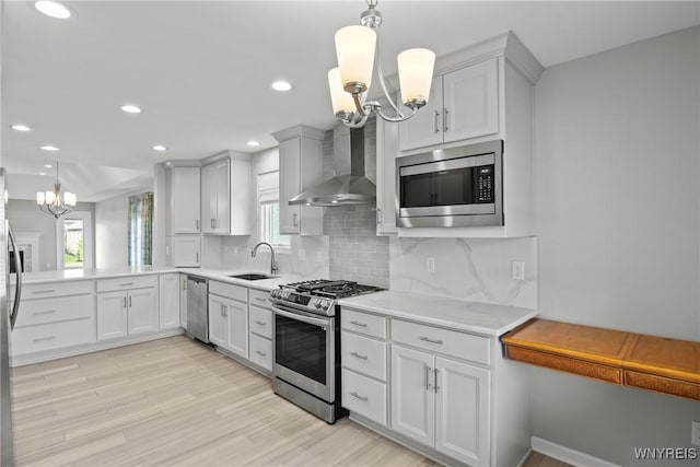29 Raine Dr, Amherst, NY 14221 - kitchen featuring stainless steel appliances, a chandelier, wall chimney exhaust hood, decorative backsplash, and light wood finished floors