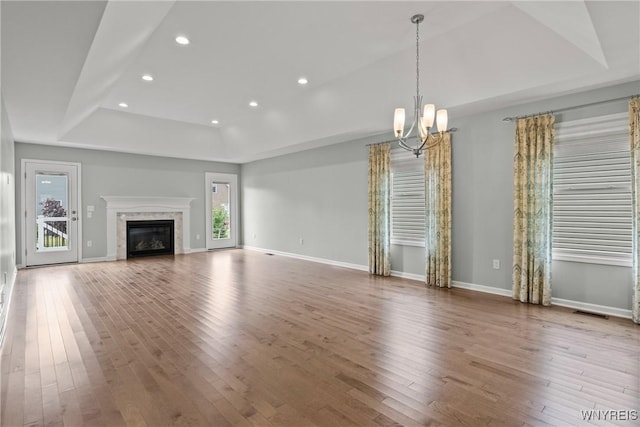 29 Raine Dr, Amherst, NY 14221 - unfurnished living room with a raised ceiling, a chandelier, wood-type flooring, recessed lighting, and a glass covered fireplace