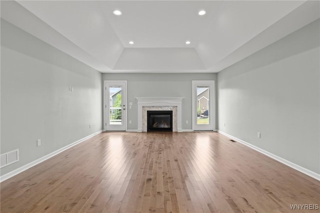29 Raine Dr, Amherst, NY 14221 - unfurnished living room featuring a tray ceiling, wood finished floors, a glass covered fireplace, and recessed lighting