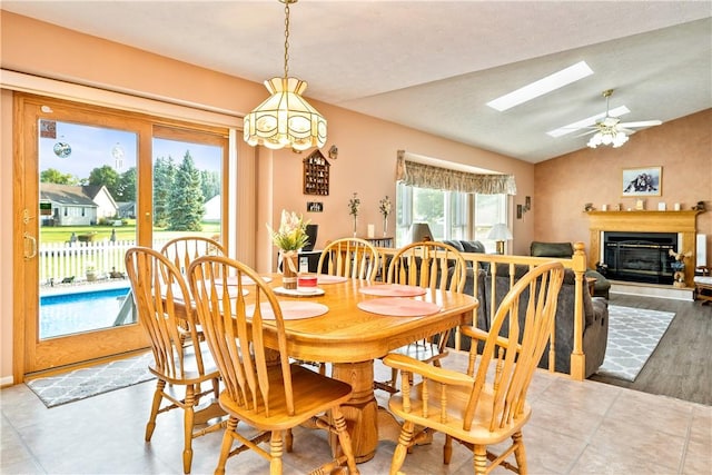 35 Silkwood Cir, Gates, NY 14559 - dining space with a glass covered fireplace, a skylight, vaulted ceiling, and a ceiling fan