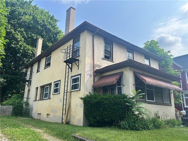 182 Parsells Ave, Rochester, NY 14609 - view of side of home with stucco siding and a chimney