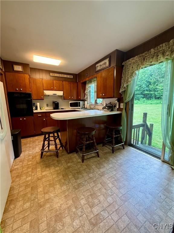 9418 Glenmore Rd Unit Es, Annsville, NY 13471 - kitchen featuring oven, brick patterned flooring, under cabinet range hood, and plenty of natural light