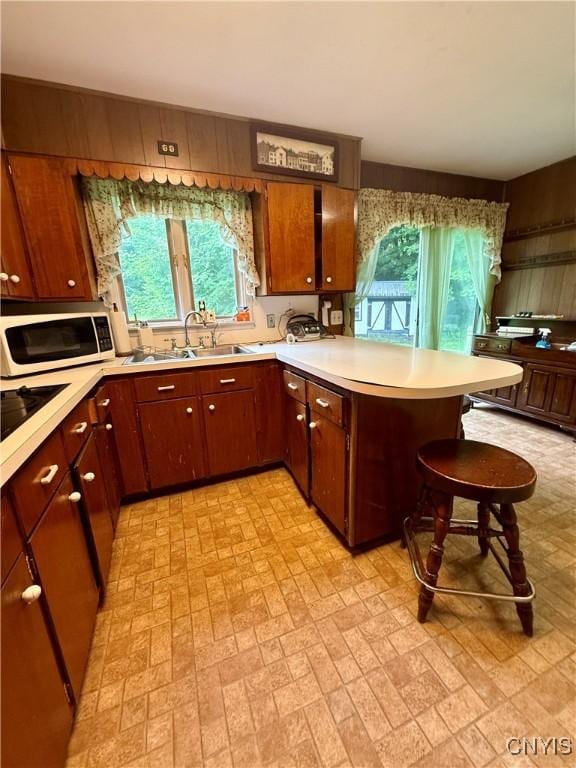 9418 Glenmore Rd Unit Es, Annsville, NY 13471 - kitchen with a peninsula, light countertops, white microwave, brick patterned floors, and a breakfast bar