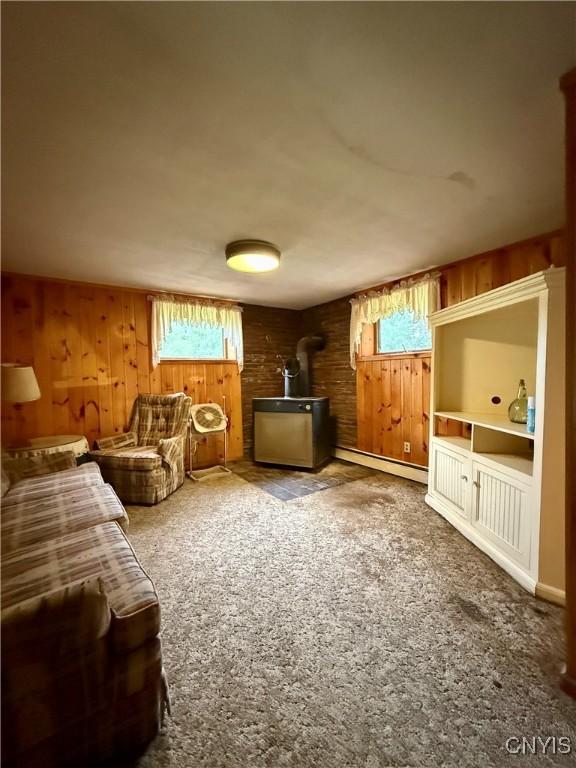 9418 Glenmore Rd Unit Es, Annsville, NY 13471 - carpeted living area with a wood stove, wood walls, and a baseboard heating unit