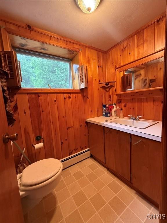9418 Glenmore Rd Unit Es, Annsville, NY 13471 - half bathroom featuring a baseboard radiator, vanity, tile patterned flooring, and wood walls