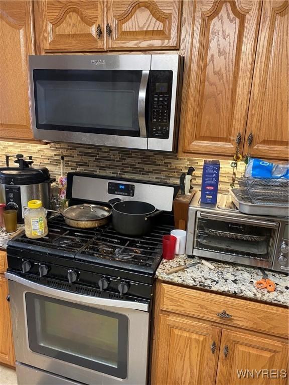 14 Princess Ln, West Seneca, NY 14224 - kitchen featuring appliances with stainless steel finishes, tasteful backsplash, brown cabinetry, and light stone counters