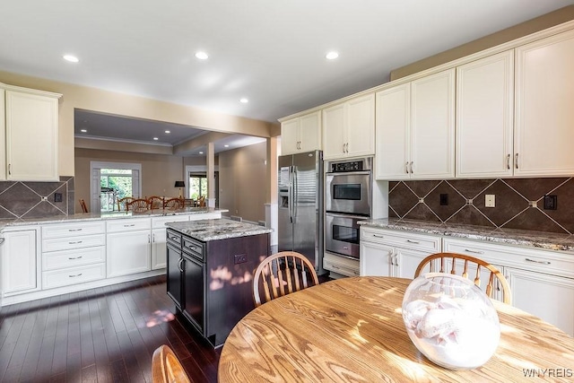171 Harbridge Mnr, Amherst, NY 14221 - kitchen with appliances with stainless steel finishes, a peninsula, dark wood finished floors, tasteful backsplash, and light stone countertops