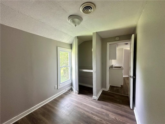 50 Saratoga Ave, Rochester, NY 14608 - unfurnished bedroom with dark wood-style floors, lofted ceiling, and a textured ceiling