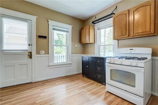 26 Fountain St, Rochester, NY 14620 - kitchen featuring white gas stove, wainscoting, light wood-type flooring, light countertops, and brown cabinets