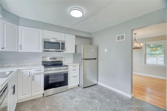 2862 Culver Rd, Irondequoit, NY 14622 - kitchen featuring appliances with stainless steel finishes, a chandelier, and white cabinets