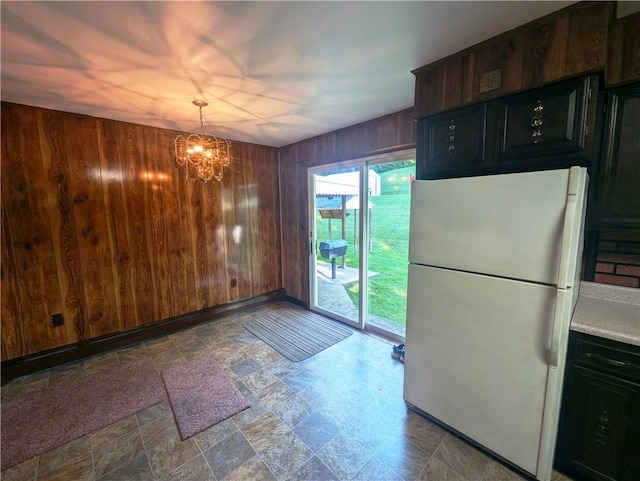 310 E Green St, Smethport Boro, PA 16749 - kitchen featuring freestanding refrigerator, wooden walls, a chandelier, stone finish flooring, and light countertops
